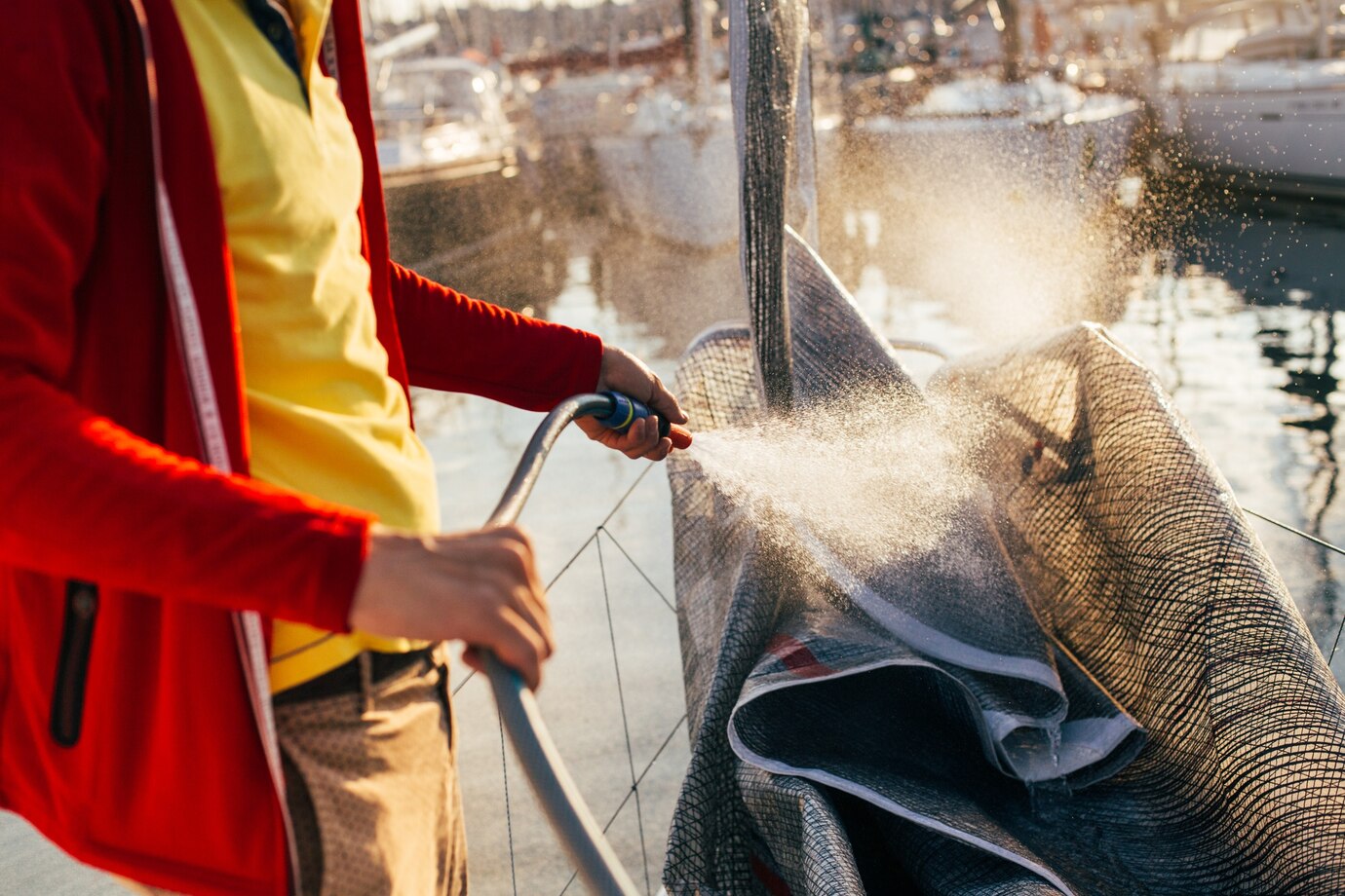 soft-focus-water-drops-come-out-hose-sailor-captain-yacht-owner-washes-salty-residue-from-sail-mainsail-spinnaker-when-sailboat-is-docked-yard-marina_346278-360